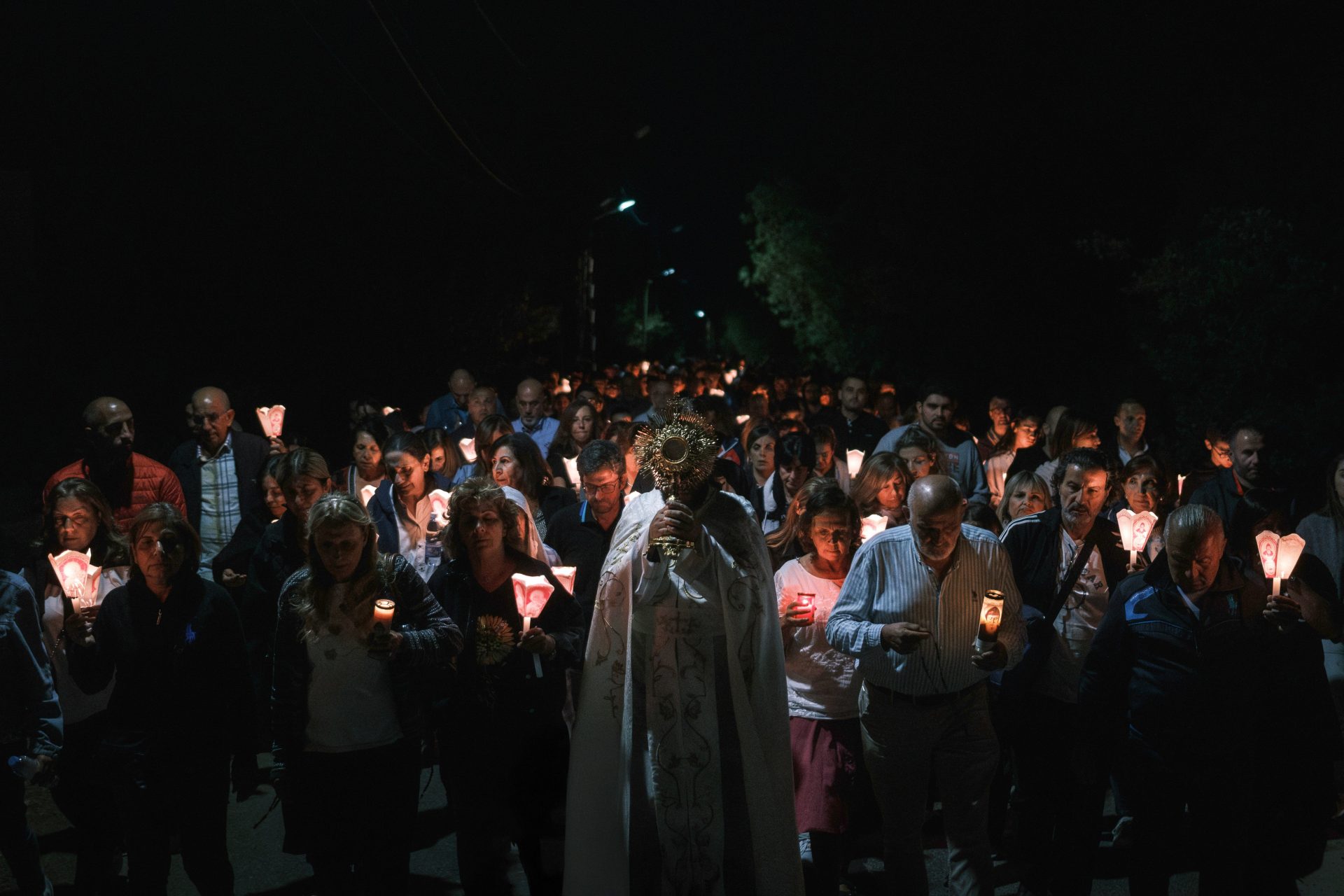 A procession of people holding candles at night